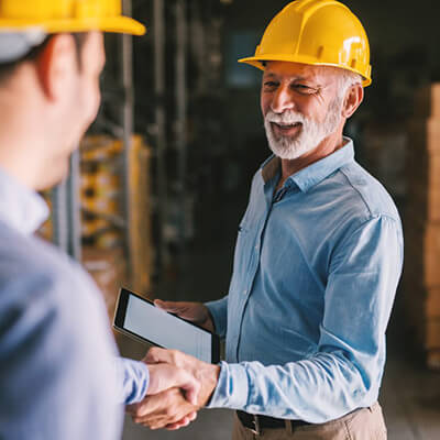 man in yellow hardhat shaking hands with another man in a hardhat
